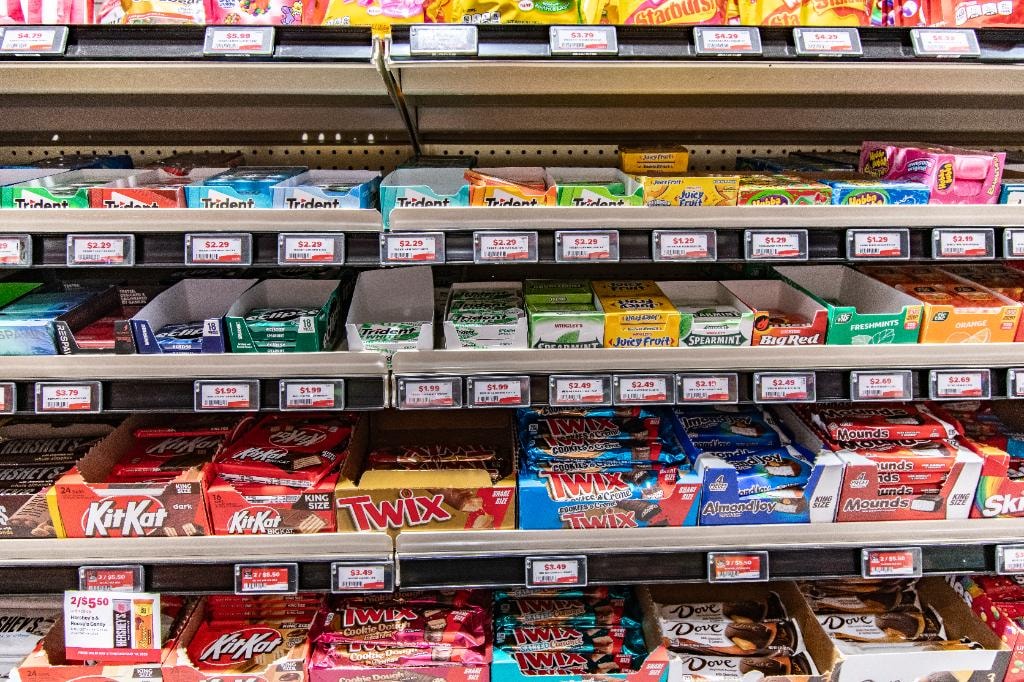 ESL – candy and gum shelf with KitKat, Twix, Trident and Starburst ESL price tags showing $1.99–$3.79